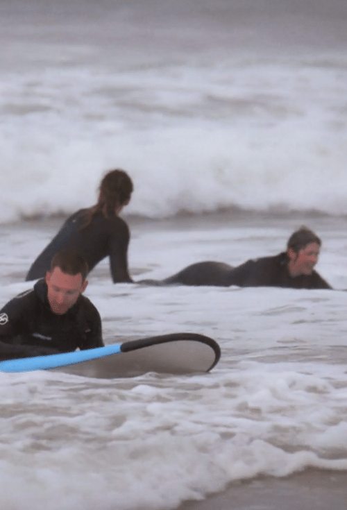 man and woman learning to surf